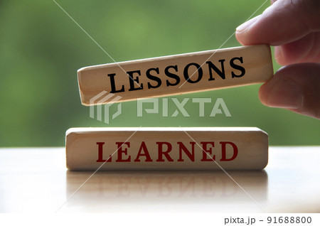 Lessons learned text on wooden blocks with hand holding and blurred nature background. Learning concept 91688800
