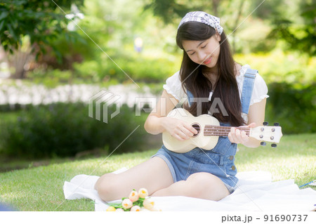 Happiness young asian woman sitting and playing ukulele while relaxation for entertainment is hobby. 91690737