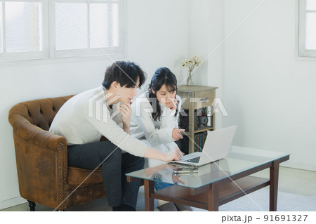 リビングでパソコンを見るカップル 91691327