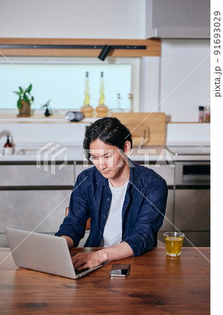 テレワークでパソコンをタイピングする若い男性 テレワークでパソコンをタイピングする若い男性 91693029