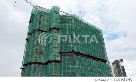 SELANGOR, MALAYSIA -JULY 16, 2018: Safety netting is installed at the high rise building exterior scaffolding during construction. Its avoid building object falling directly to the ground. SELANGOR, MALAYSIA -JULY 16, 2018: Safety netting is installed at the high rise building exterior scaffolding during construction. Its avoid building object falling directly to the ground. 91693840