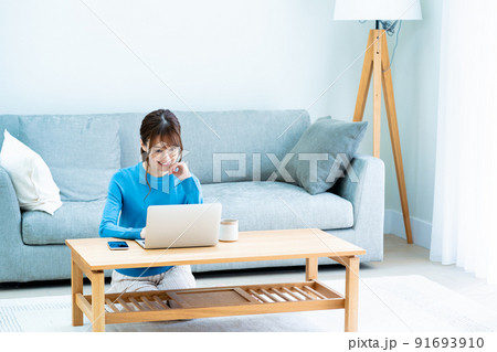 リビングでノートパソコンを使う眼鏡の女性 91693910