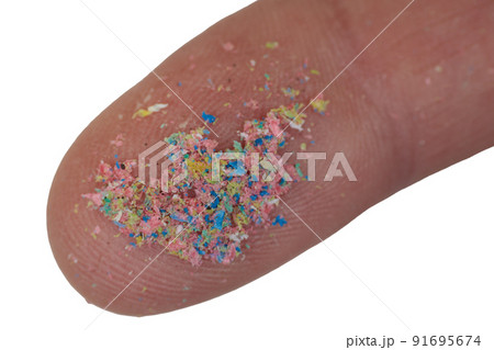 Macro close-up of a microplastic on the finger of the hand. Isolated on white background. Macro close-up of a microplastic on the finger of the hand. Isolated on white background. 91695674