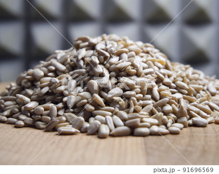 A pile of peeled sunflower seeds on a wooden surface, macro shot. 91696569