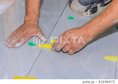 Working with a tile leveling system that uses plastic clips and wedges in bathroom construction Working with a tile leveling system that uses plastic clips and wedges in bathroom construction 91696972
