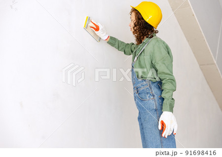 Young woman, professional builder makes room repairs using different work tools. Gender equality. Work, occupation, apartment renovation. Young woman, professional builder makes room repairs using different work tools. Gender equality. Work, occupation, apartment renovation. 91698416