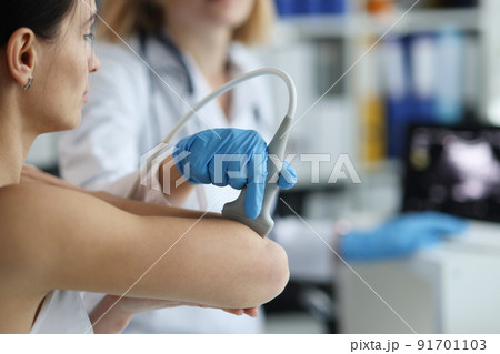 Patient with orthopedic doctor makes ultrasound of elbow joint in clinic 91701103