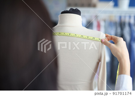 Fashion designer stylist takes measurements with centimeter from clothes on mannequin 91701174