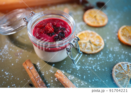 closeup of berry panna cotta dessert with cherry sauce in glass jar on table 91704221