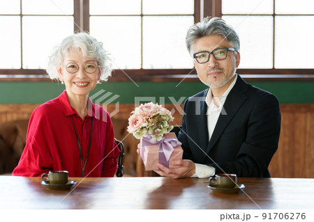 花束とプレゼントを渡す中高年の夫婦 91706276