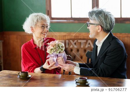 花束とプレゼントを渡す中高年の夫婦 91706277