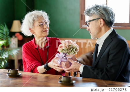 花束とプレゼントを渡す中高年の夫婦 91706278