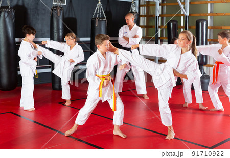 Kids in kimonos exercising techniques in pair during taekwondo class 91710922