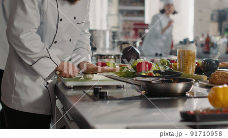 Male cook preparing garlic to add to aromatic food recipe, making delicious meal with fresh ingredients and utensils. Gourmet chef using vegetables to make dish preparations. Handheld shot. 91710958