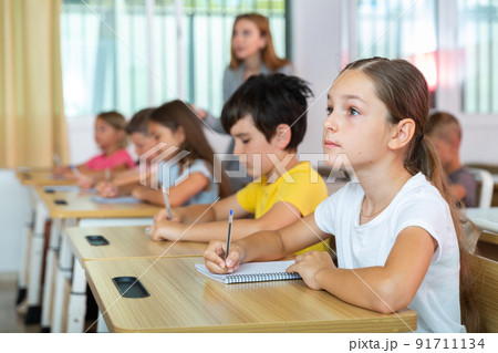 Schoolgirl sitting in classroom during lesson in elementary school 91711134