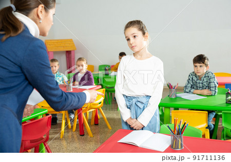 Upset schoolgirl listening reprimanding of teacher 91711136