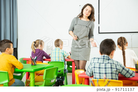 Female teacher and pupils working in classroom at elementary school 91711137