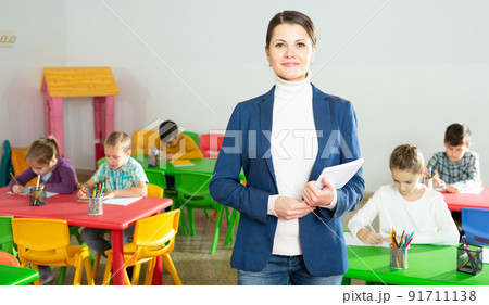 Smiling teacher standing in classroom Smiling teacher standing in classroom 91711138