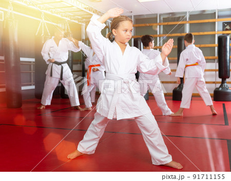 Girl fighting karate stand in the gym. Children in pair practice karate 91711155