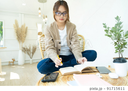Young collage student reading a book sitting in a chair.. 91715611