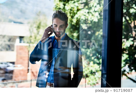 Taking care of business. Shot of a young businessman talking on the phone outside an office. 91719087