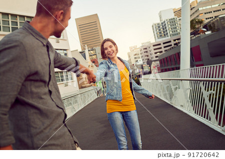 Romantic city strolls. Shot of a happy young couple enjoying a romantic walk together in the city. 91720642