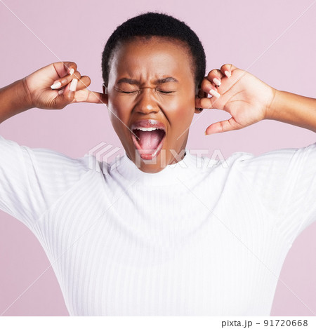Blocking out the negativity. Studio shot of a young woman holding her fingers to close her ears against a pink background. 91720668