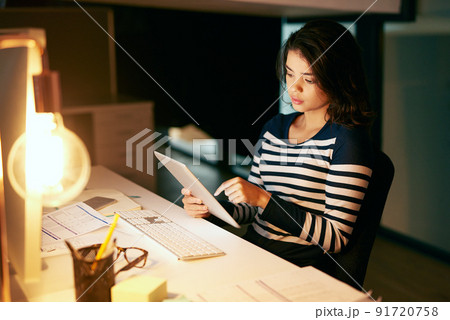 Shes as equally productive through the day and night. Shot of a young businesswoman working late on a digital tablet in an office. Shes as equally productive through the day and night. Shot of a young businesswoman working late on a digital tablet in an office. 91720758