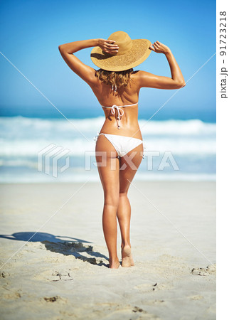 Feeling hot, hot, hot. Rearview shot of a gorgeous young woman in a bikini at the beach. Feeling hot, hot, hot. Rearview shot of a gorgeous young woman in a bikini at the beach. 91723218