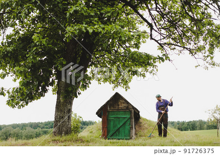 Man working in the garden with rake in a sunny day. Farmer working in the backyard Man working in the garden with rake in a sunny day. Farmer working in the backyard 91726375