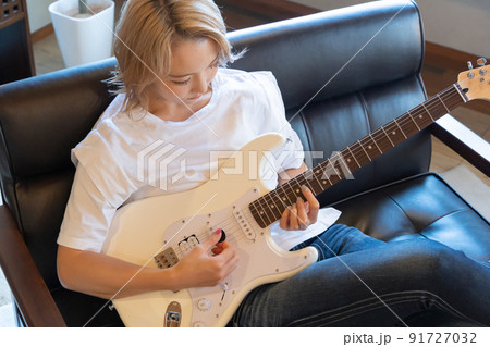 白いエレキギターを弾く若い女性 91727032