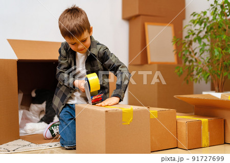 Little boy packing a moving box for a new home Little boy packing a moving box for a new home 91727699