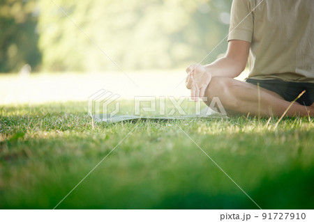 For body stress release. Cropped shot of a man sitting in the lotus position on the grass. 91727910