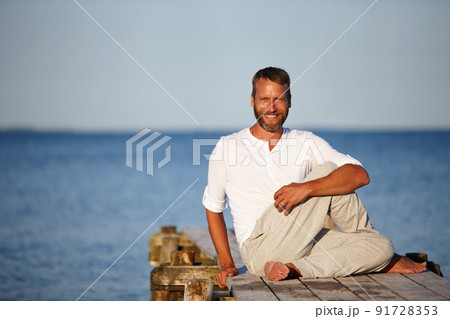 Stretching his muscles to stay flexible. Portrait of a handsome mature man doing yoga on a pier out on the ocean. Stretching his muscles to stay flexible. Portrait of a handsome mature man doing yoga on a pier out on the ocean. 91728353