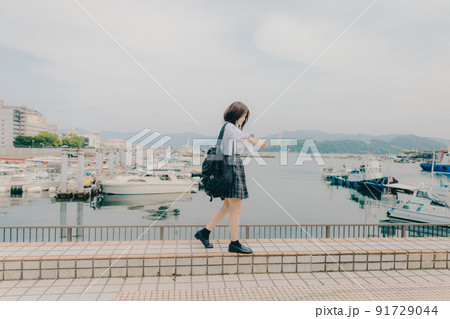 制服姿の女子高生と綺麗な海岸風景 91729044