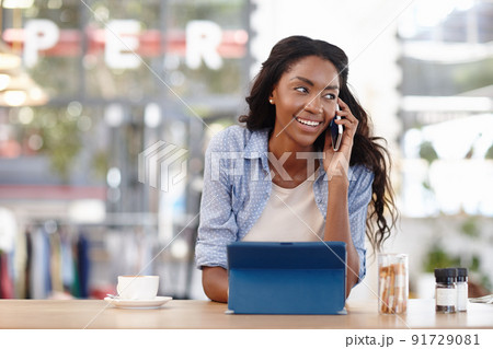 Im waiting for you at the coffee shop. Cropped shot of an attractive woman sitting in a coffee shop using a cellphone and tablet. Im waiting for you at the coffee shop. Cropped shot of an attractive woman sitting in a coffee shop using a cellphone and tablet. 91729081