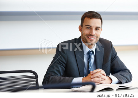 Ready to help. A handsome young businessman sitting at his desk with a smile. Ready to help. A handsome young businessman sitting at his desk with a smile. 91729225