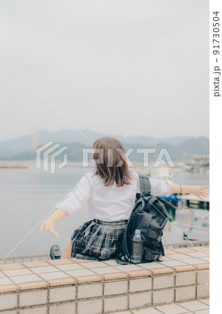 制服姿の女子高生と綺麗な海岸風景 91730504