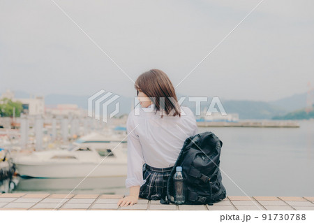制服姿の女子高生と綺麗な海岸風景 91730788