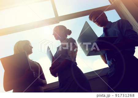 On their way to the top. Silhouette of three young businesspeople standing in front of a window. On their way to the top. Silhouette of three young businesspeople standing in front of a window. 91731268