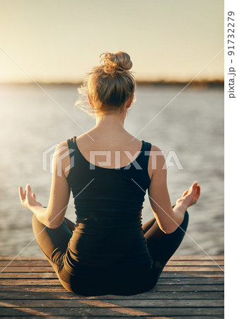 Mental fitness is just as important as physical. Rearview shot of a young woman meditating outdoors. 91732279