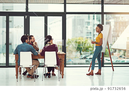 Great minds achieving great things. Shot of a young creative giving a presentation to her colleagues in an office. Great minds achieving great things. Shot of a young creative giving a presentation to her colleagues in an office. 91732656