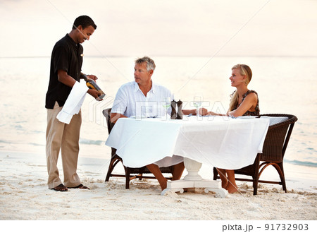 Mature couple having dinner at the beach. Shot of a mature couple enjoying a romantic dinner on the beach. 91732903