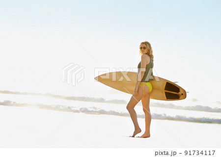 Enjoying the sunshine. A young surfer girl on the beach during the summer time. 91734117