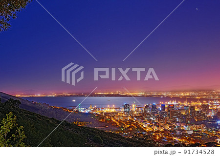 Signal Hill in Cape Town South Africa with copyspace against dark night sky background and the view of a coastal city. Scenic panoramic landscape of lights illuminating an urban skyline along the sea 91734528