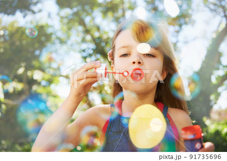Bubbles and summer vacation. Shot of a cute young girl blowing bubbles outside. Bubbles and summer vacation. Shot of a cute young girl blowing bubbles outside. 91735696
