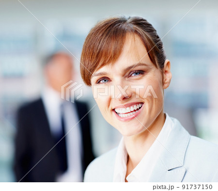 Happy female executive with colleagues in background. Focus on happy female executive with team behind her. Happy female executive with colleagues in background. Focus on happy female executive with team behind her. 91737150