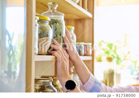 Storage of food in the kitchen in pantry, woman's hands with a can Storage of food in the kitchen in pantry, woman's hands with a can 91738000