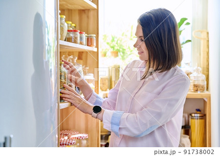Young woman in kitchen with containers jars of food 91738002