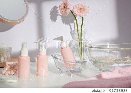 Front view of cosmetic jar in white bathroom with glassware and flower for cosmetic advertising , lifestyle content Front view of cosmetic jar in white bathroom with glassware and flower for cosmetic advertising , lifestyle content 91738983